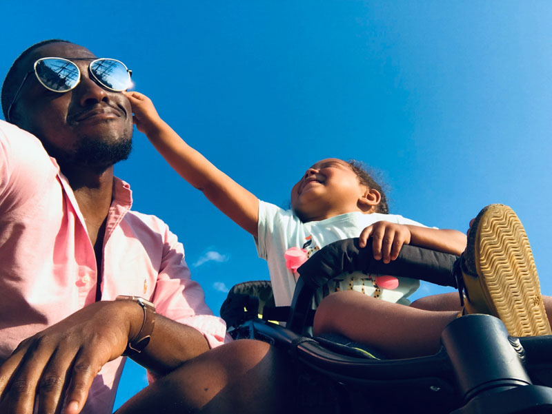 Mädchen im Kinderwagen und der Vater kniend daneben