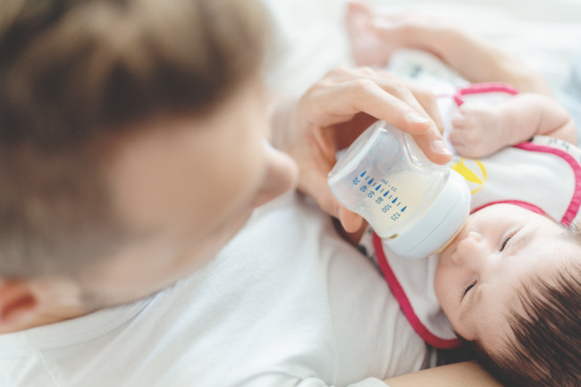 Young father feeding baby with bottle of milk. Baby family concept. Lifestyle