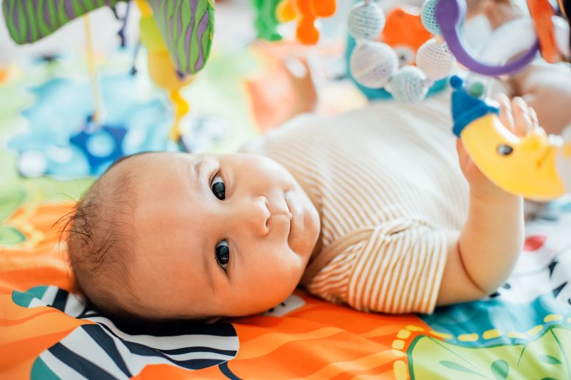baby-liegt-auf-einer-spielmatte