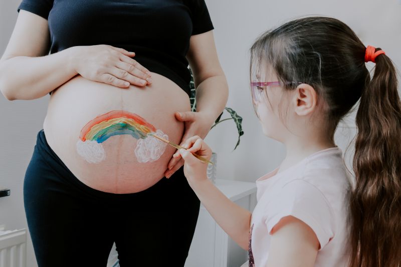 maedchen-bemalt-babybauch-mit-regenbogen